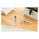 Pacidose pacifier and liquid medicine dispenser set on a wooden surface, with a towel and plant in the background.