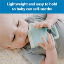Baby uses Dr. Brown Ridgees Blue Tumbler Massaging Teether to self-soothe, holding it comfortably while lying down.