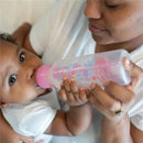 A mother feeds a baby with a Dr. Brown’s 8 oz pink floral anti-colic bottle, demonstrating bonding and care.