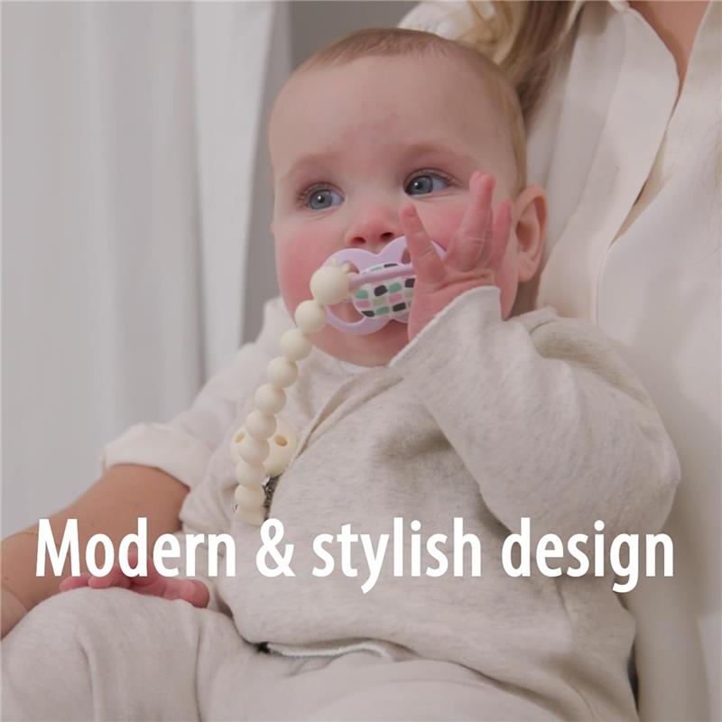 Gray and green silicone pacifier clip is held by a baby in a cozy outfit, showcasing its modern design.