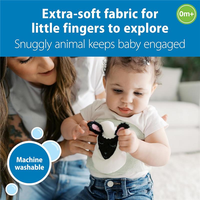 Infant girl exploring a soft Lamb Gripebelt toy, held by her mother, emphasizing its extra-soft fabric and machine washability.