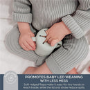 Seafoam Dreambaby Drink & Snack Cup held by a child in soft grey clothing, designed for mess-free baby-led weaning.