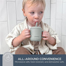 Child holding a seafoam Dreambaby Drink & Snack Cup with a straw, sitting against a tiled background.
