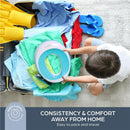 Dreambaby Potty Trainer Seat in aqua held by a child, surrounded by clothes and travel items in an open suitcase.