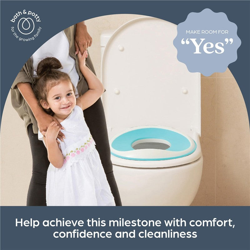 A young girl in a white dress holds hands with an adult next to a toilet fitted with a blue Dreambaby Potty Trainer Seat.