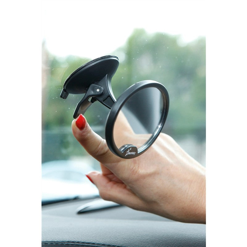 Hand holding the Dreambaby Ezy-View Baby View Mirror, a round mirror with a suction cup mount, against a car window.