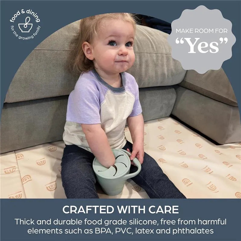 Foldable seafoam snack cup held by a toddler, showcasing its silicone design for safe eating.
