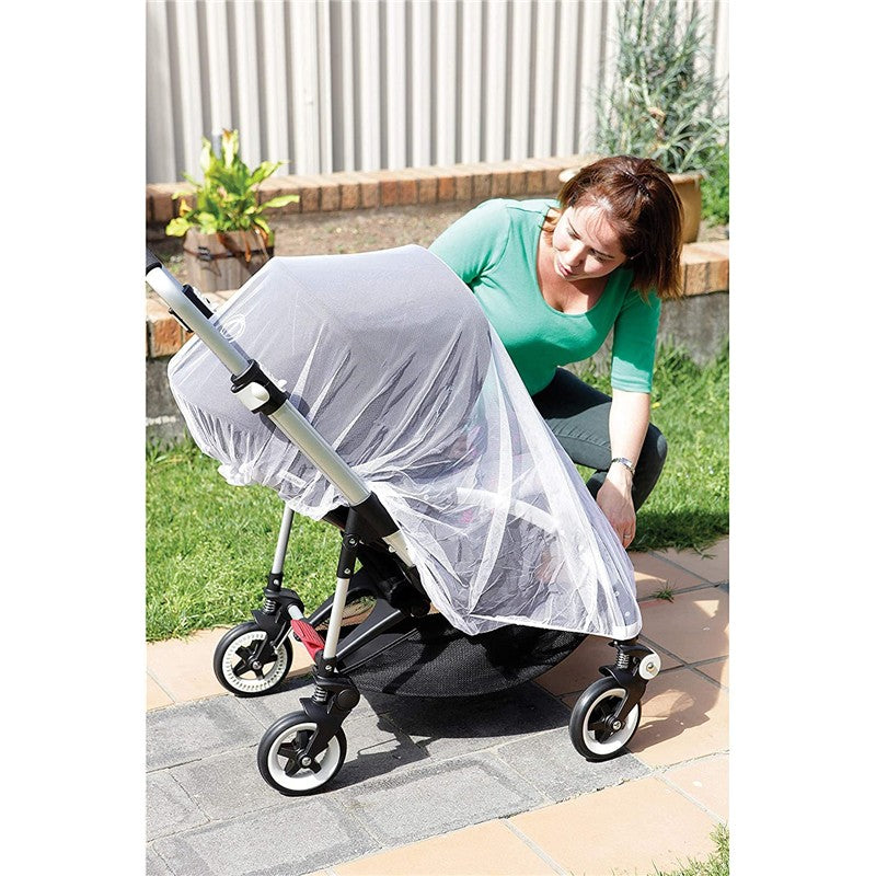 A woman adjusts a Dreambaby stroller insect netting over a stroller, protecting it from insects outdoors.