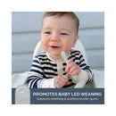Smiling baby in a striped outfit holds a seafoam green spoon, promoting baby-led weaning and teething relief.