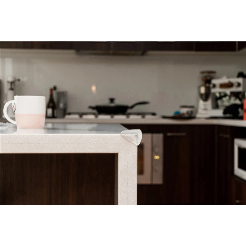 Soft Touch Corner Cushion on a table corner with a cup nearby, designed for child safety by preventing sharp edge injuries.