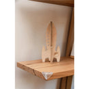 Clear corner cushion placed on a wooden shelf beside a wooden rocket toy, enhancing safety for children.