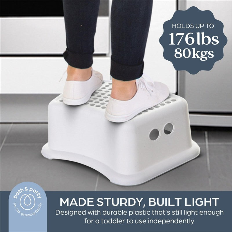 Grey dot-patterned plastic step stool with a person’s feet on it, designed for children to reach higher surfaces, supports up to 176 lbs.