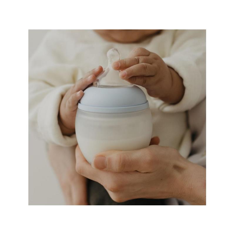 Silicone bottle nipple atop a baby bottle, held by an adult and baby, showcasing its design for feeding.