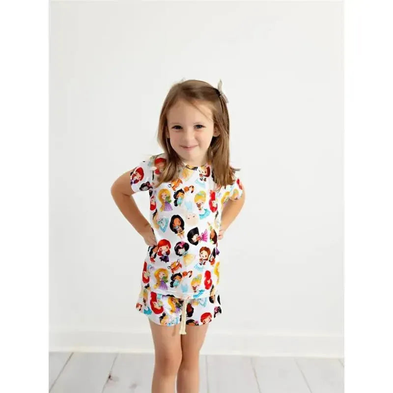 Young girl wearing the Ellie Sue Princess Bamboo Lounge Set, featuring colorful character prints, smiling confidently.