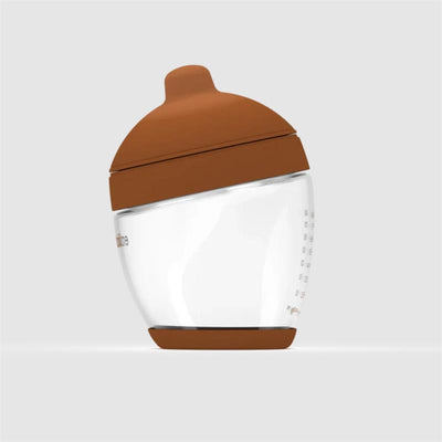Glass bottle with a deep brown nipple lid, designed for feeding, indicating measurement markings on the side.