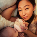A woman gently feeds a baby with a medium-sized classic glass bottle featuring a clear nipple in a cozy setting.
