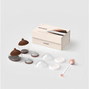 Emulait Starter Kit featuring two clear nipples with brown tops, several nipple shapes, and a cleaning brush in a box.
