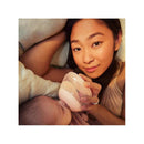 Mother feeds an infant with a pink feeding bottle while reclining, showcasing a cozy, intimate moment.