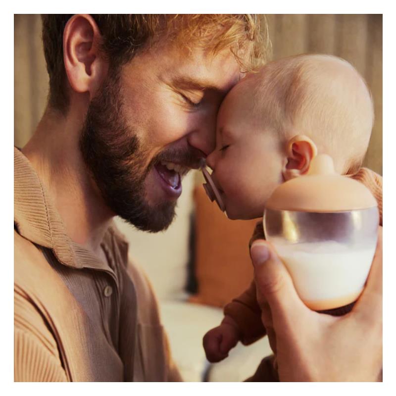 Father and baby sharing a joyful moment, with the baby holding an Emulait bottle featuring a classic nipple design.