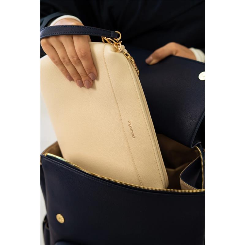 A hand placing a beige clutch into the interior of a navy blue Enya Mond Nova Bag.