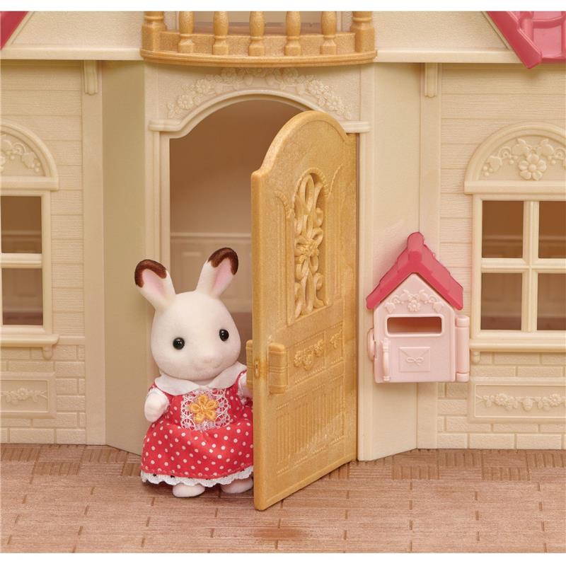 Calico Critters dollhouse featuring a rabbit figure in a red polka dot dress at the front door with a mailbox nearby.