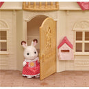 Calico Critters dollhouse featuring a rabbit figure in a red polka dot dress at the front door with a mailbox nearby.