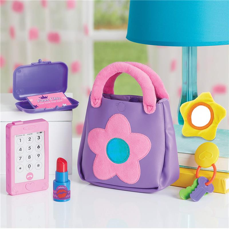 Toddler pretend play set featuring a purple purse with a pink flower, a toy phone, lipstick, and accessories including a mirror and keys.