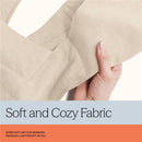 Soft beige fabric of the Ergobaby Embrace Baby Carrier held in a hand, highlighting its cozy texture and lightweight design.