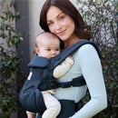 Mother wearing an Ergobaby Omni Classic Baby Carrier in Midnight Blue, holding a baby.