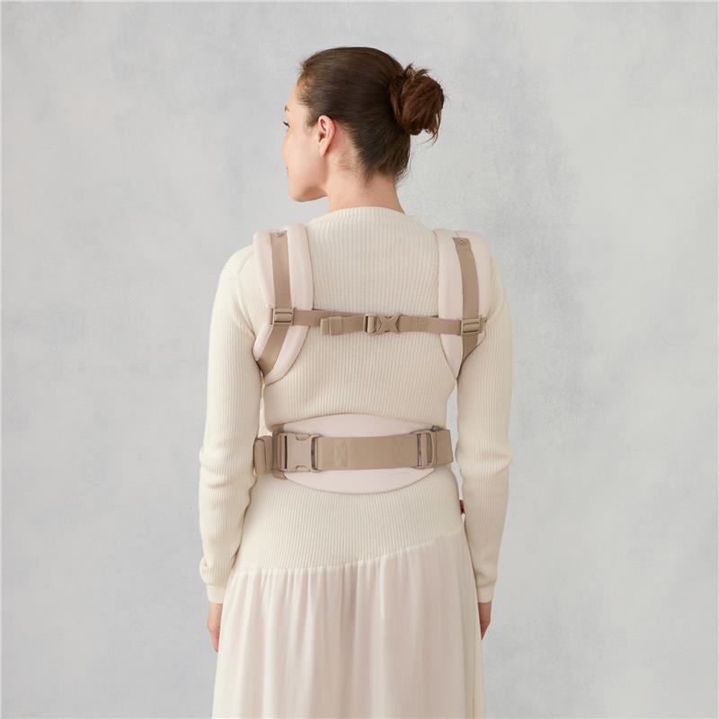 Ergobaby Omni Classic Baby Carrier in natural beige, worn by a woman, showing adjustable straps and back support.