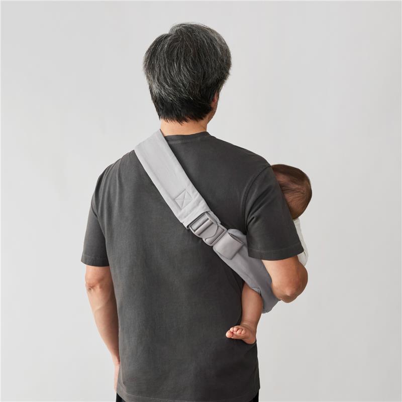 Ergobaby Upsie Sling Baby Carrier in pearl grey worn by a man carrying a toddler on his hip.