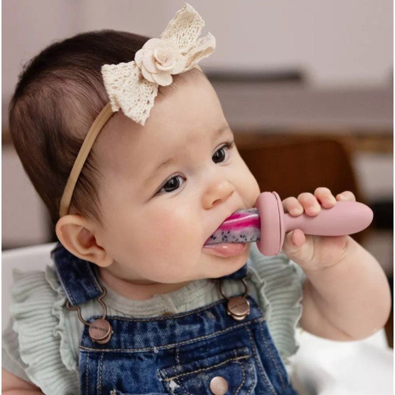Baby using the ezpz Baby Led Gumline Feeder Straight Pack in blush color, enjoying a colorful food blend.