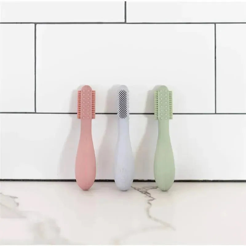 Ezpz Baby-Led Toothbrush and Sensory Tongue Depressor Dual Pack in pink, gray, and green on a white tile background.