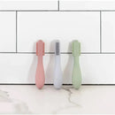 Ezpz Baby-Led Toothbrush and Sensory Tongue Depressor Dual Pack in pink, gray, and green on a white tile background.