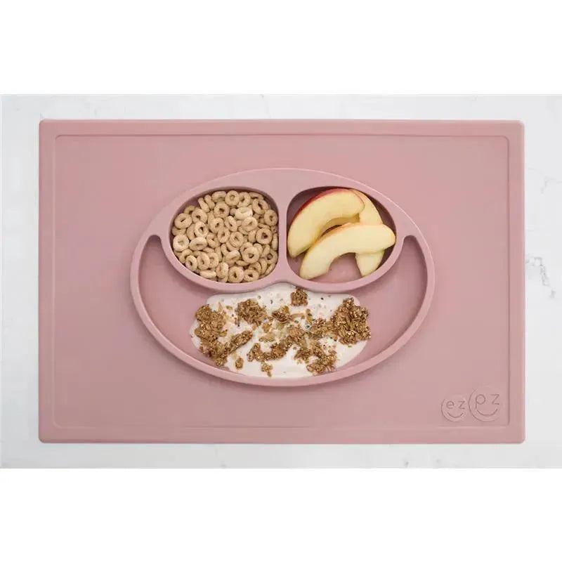 Silicone mat in blush color with three compartments holding apple slices, cereal, and granola on yogurt.