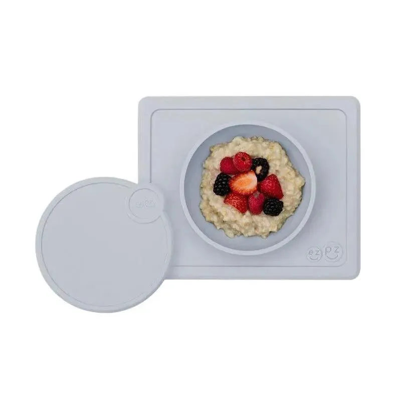 Ezpz Mini Bowl Lid in pewter color, with oatmeal topped with berries in a round bowl, displayed on a rectangular mat.