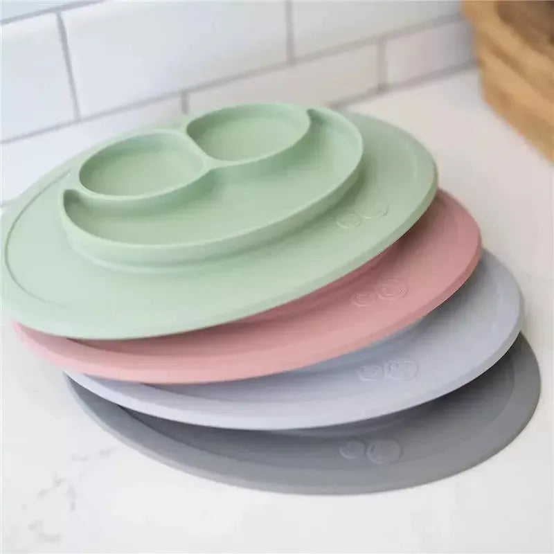 Ezpz Mini Mat in pewter color, featuring sections for food, with a durable silicone design stacked with green, pink, and gray mats.