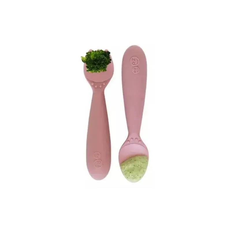 Two blush pink mini utensils designed for toddlers, featuring a spoon with broccoli and another with green food.