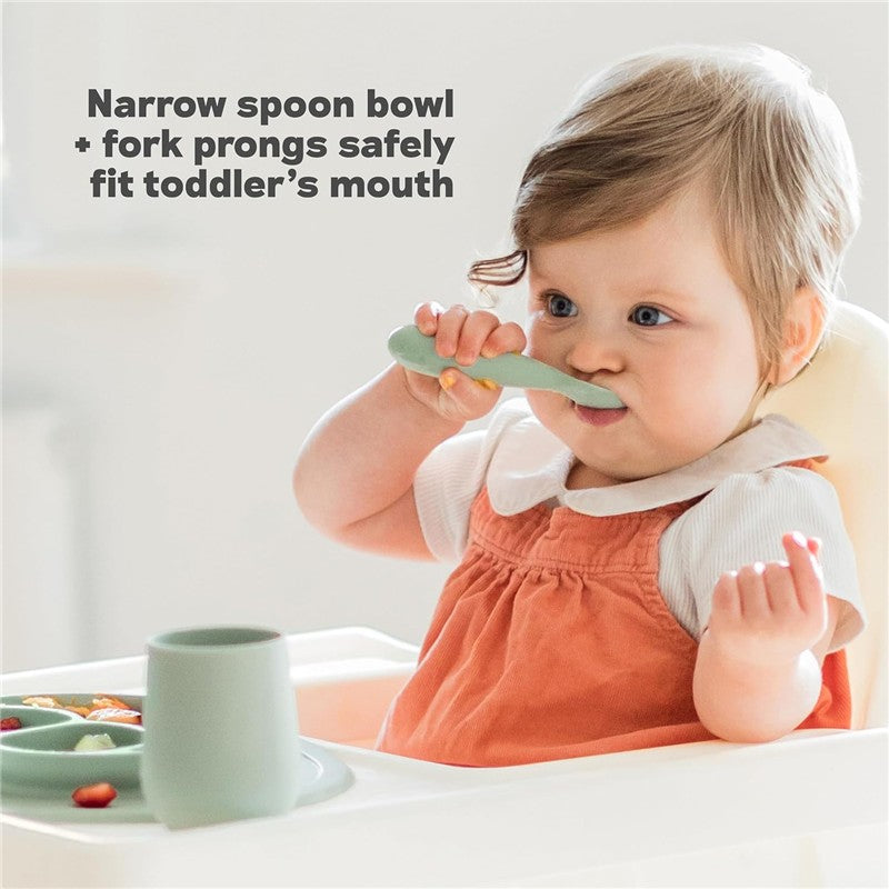 Toddler using a sage green Ezpz mini spoon while sitting in a high chair, surrounded by colored fruit on a divided plate.