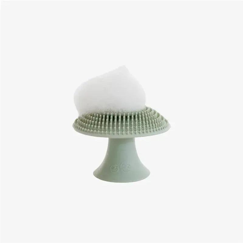 Sage green Ezpz Mushroom Sponge with a textured surface and a fluffy white top for effective cleaning.