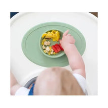 Sage-colored Ezpz Tiny Bowl with assorted finger foods, including fruit pieces, on a high chair tray.