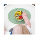 Sage-colored Ezpz Tiny Bowl with assorted finger foods, including fruit pieces, on a high chair tray.