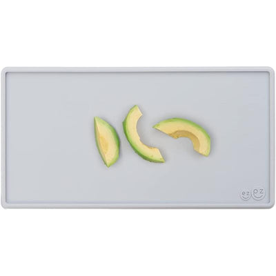 Tiny pewter-colored placemat with three avocado slices arranged on it.
