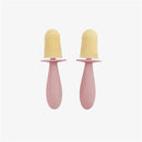 Tiny pink popsicle molds with wands, featuring yellow frozen treats with a textured top for easy gripping.