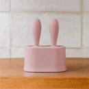 Tiny pink silicone popsicle mold set with two wands, designed for making frozen treats, placed on a wooden surface.