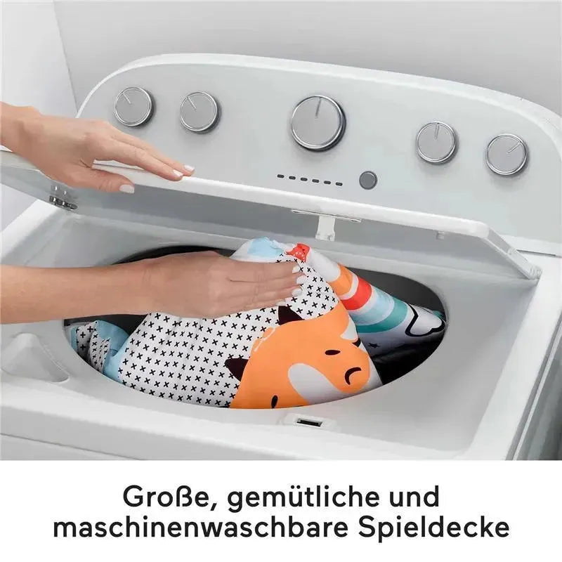 3-in-1 Music, Glow and Grow Gym Play Mat being placed in a washing machine, showcasing its machine-washable feature.