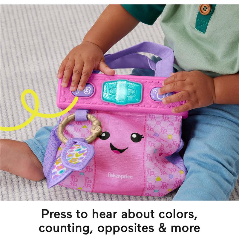 Fisher Price Baby Learning Toy Laugh & Learn Purse in pink, featuring buttons and a smiling face, being held by a child.
