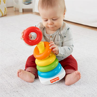Baby playing with a Fisher Price Rock-A-Stack toy, stacking colorful rings on a white base.