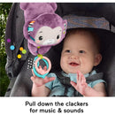 Purple monkey plush toy with dangling rings engages a smiling baby in a stroller, promoting sensory play and music.