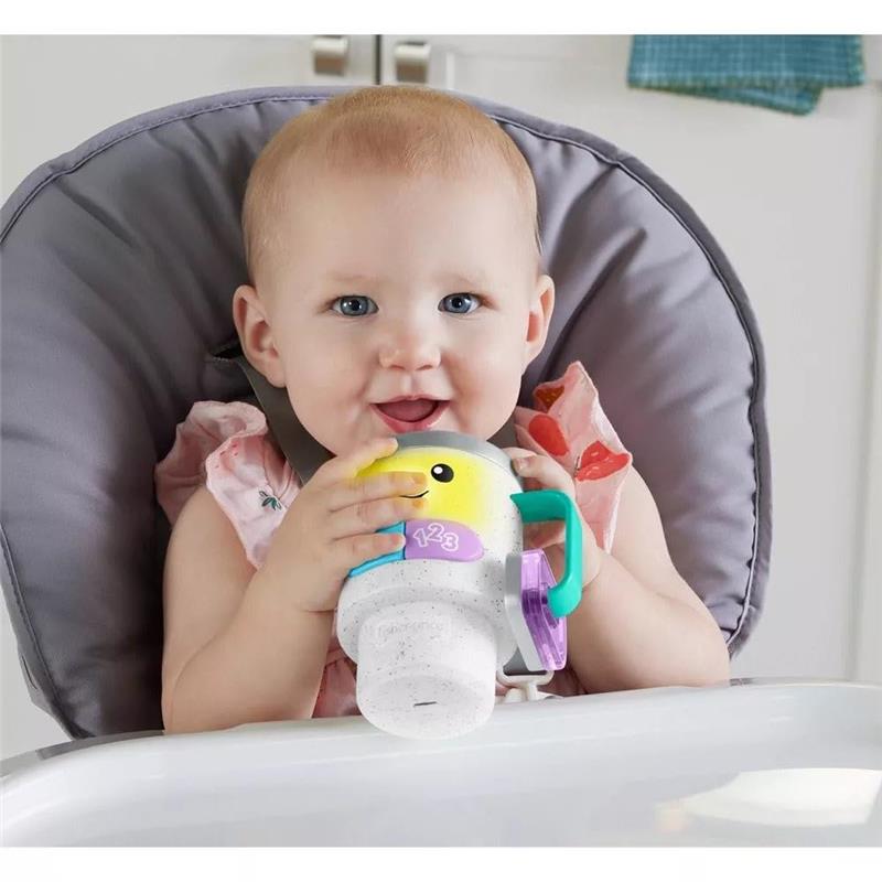 Toddler sitting in a high chair holding a Fisher Price Laugh & Learn coffee mug toy with lights and sounds.